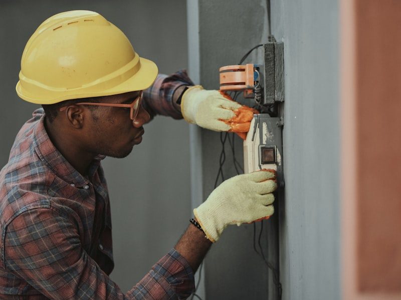 Electrician in a hard hat working on an exterior electrical box