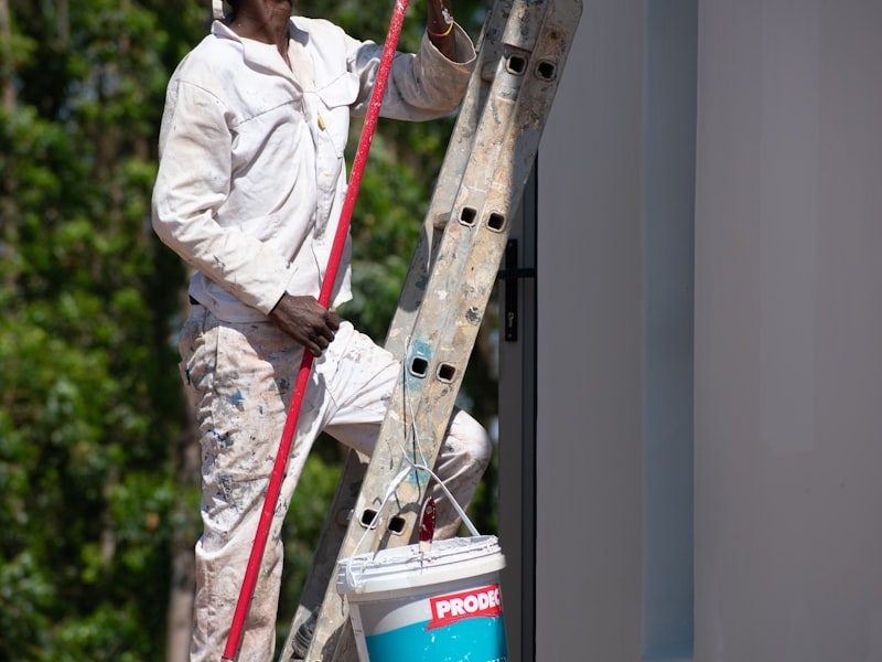 Painter on a ladder painting a house exterior