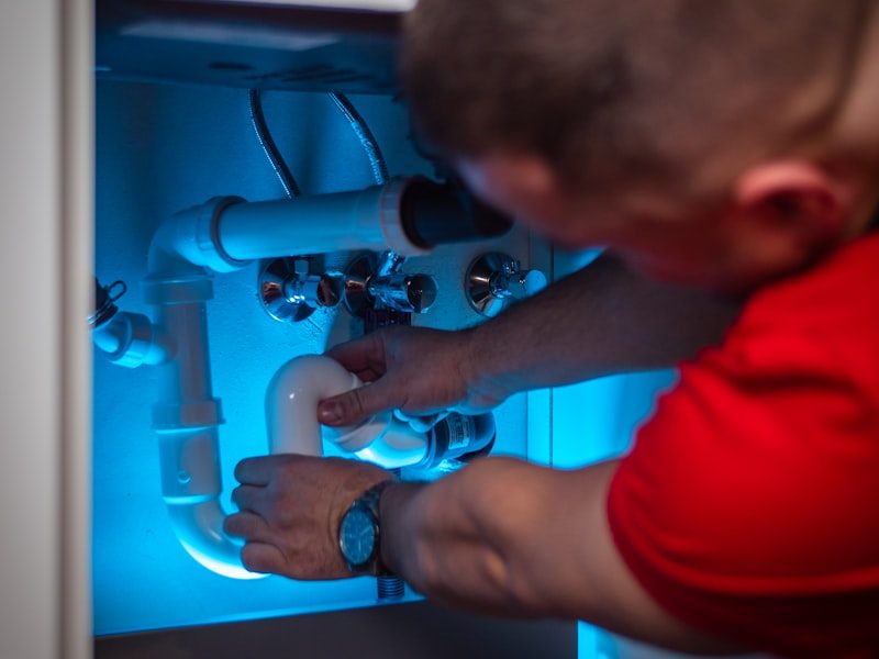 Plumber repairing pipes under a sink